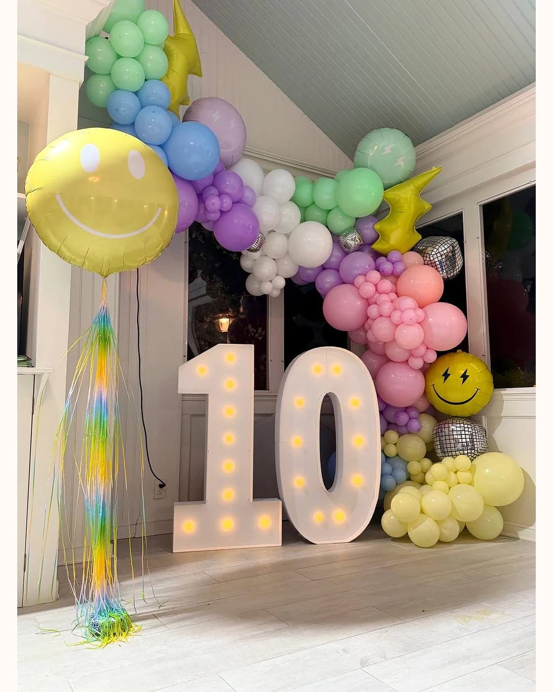 Alternate angle of a pastel tenth birthday balloon installation with marquee numbers