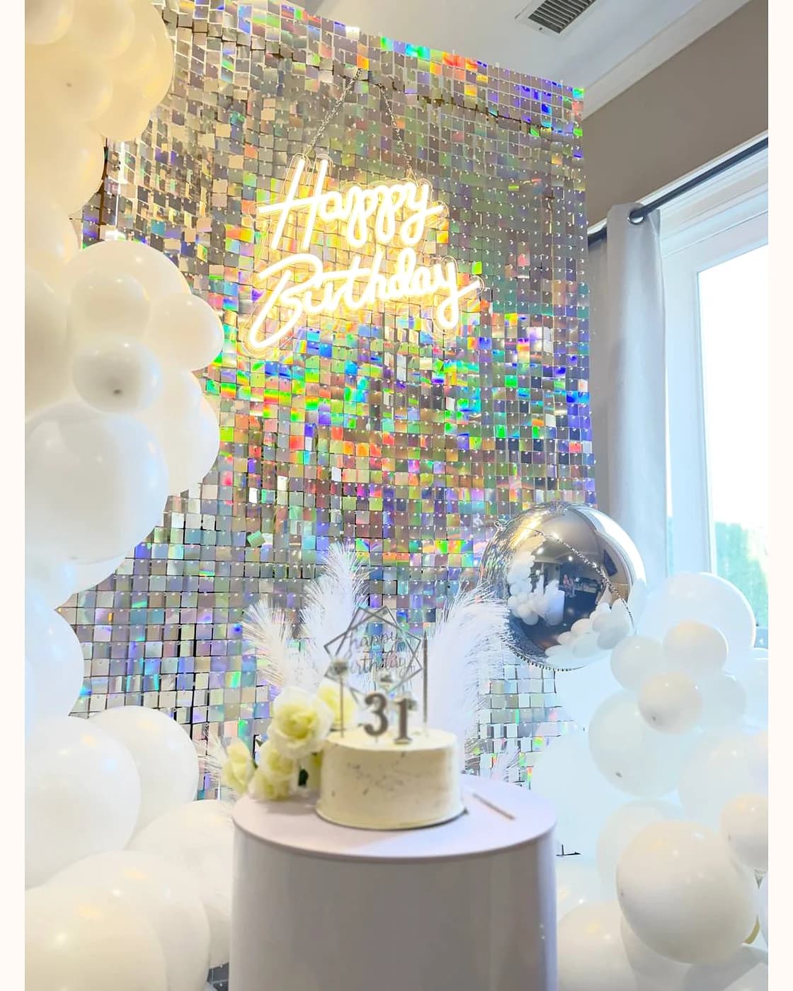 White balloon installation with shimmer wall and styled birthday setup