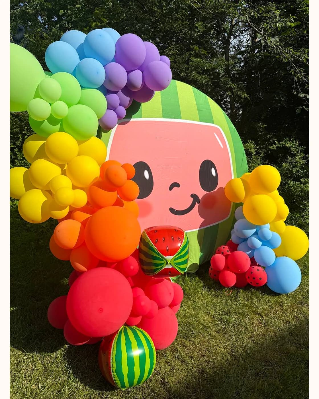 Colorful watermelon themed balloon backdrop for a kids party outdoors