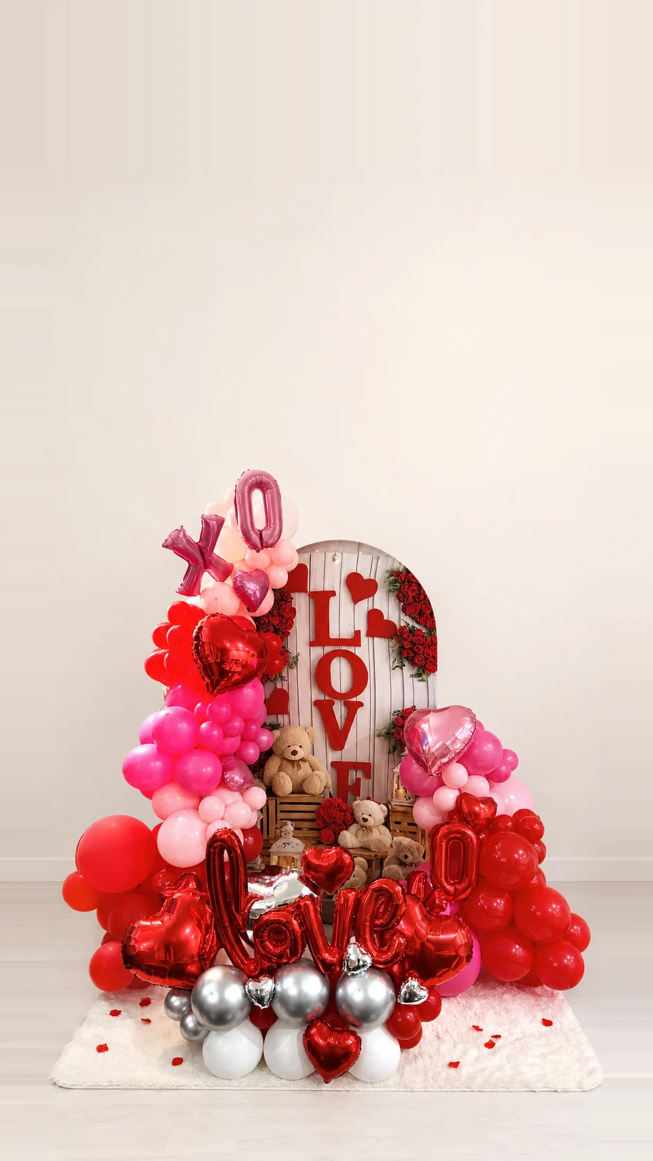 Red and pink Valentine balloon installation with a LOVE backdrop and teddy bears